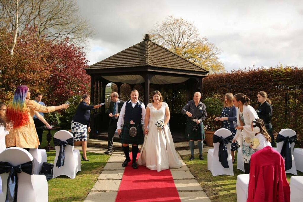 Eastbourne_wedding_photographer_deans_place_hotel_powell-ful_photography.4 bride and groom walking down the isle with guest throwing confetti