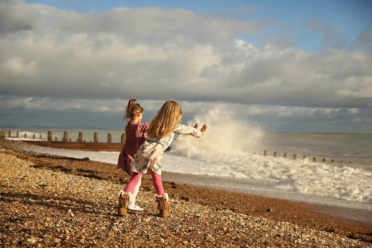 eastbourne_photographer_beach_photo_shoot__powell-ful_photography two young girls on the beach moving there hands towards the waves