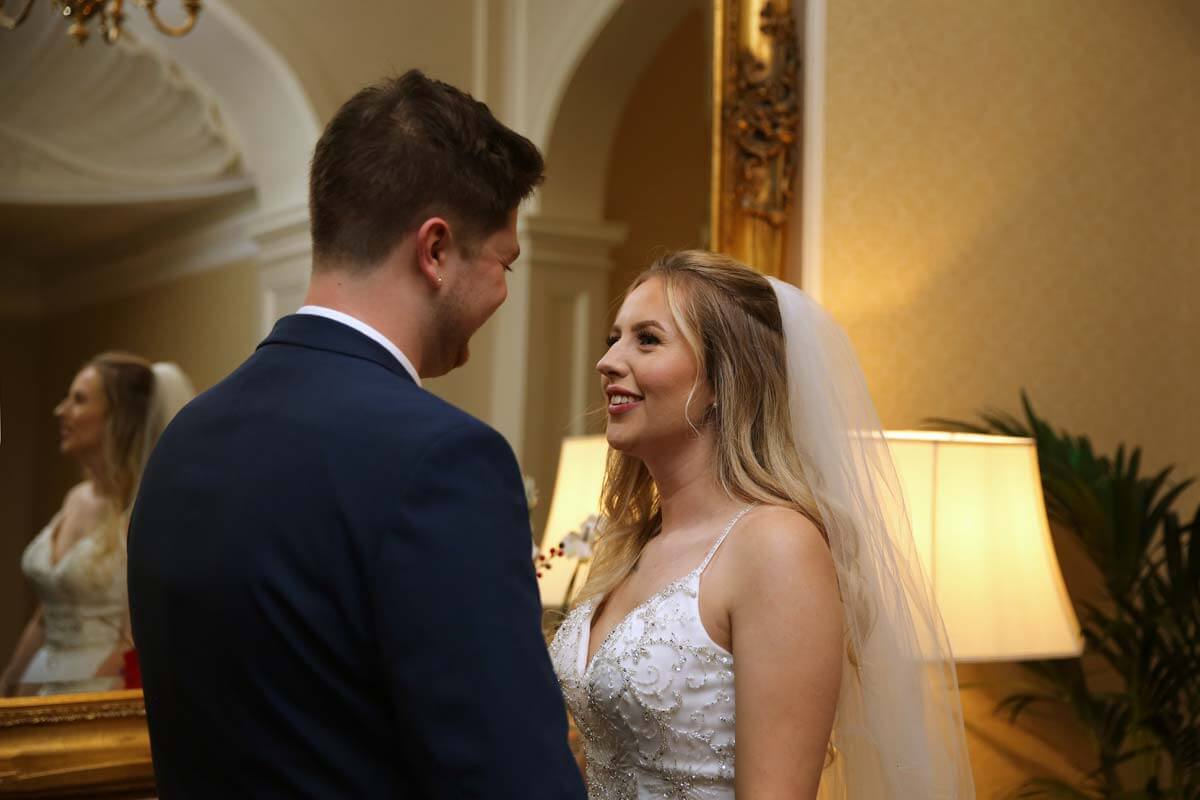 wedding photography, The Grand Hotel Eastbourne. Bride and groom standing in front a mirror. looking at each other