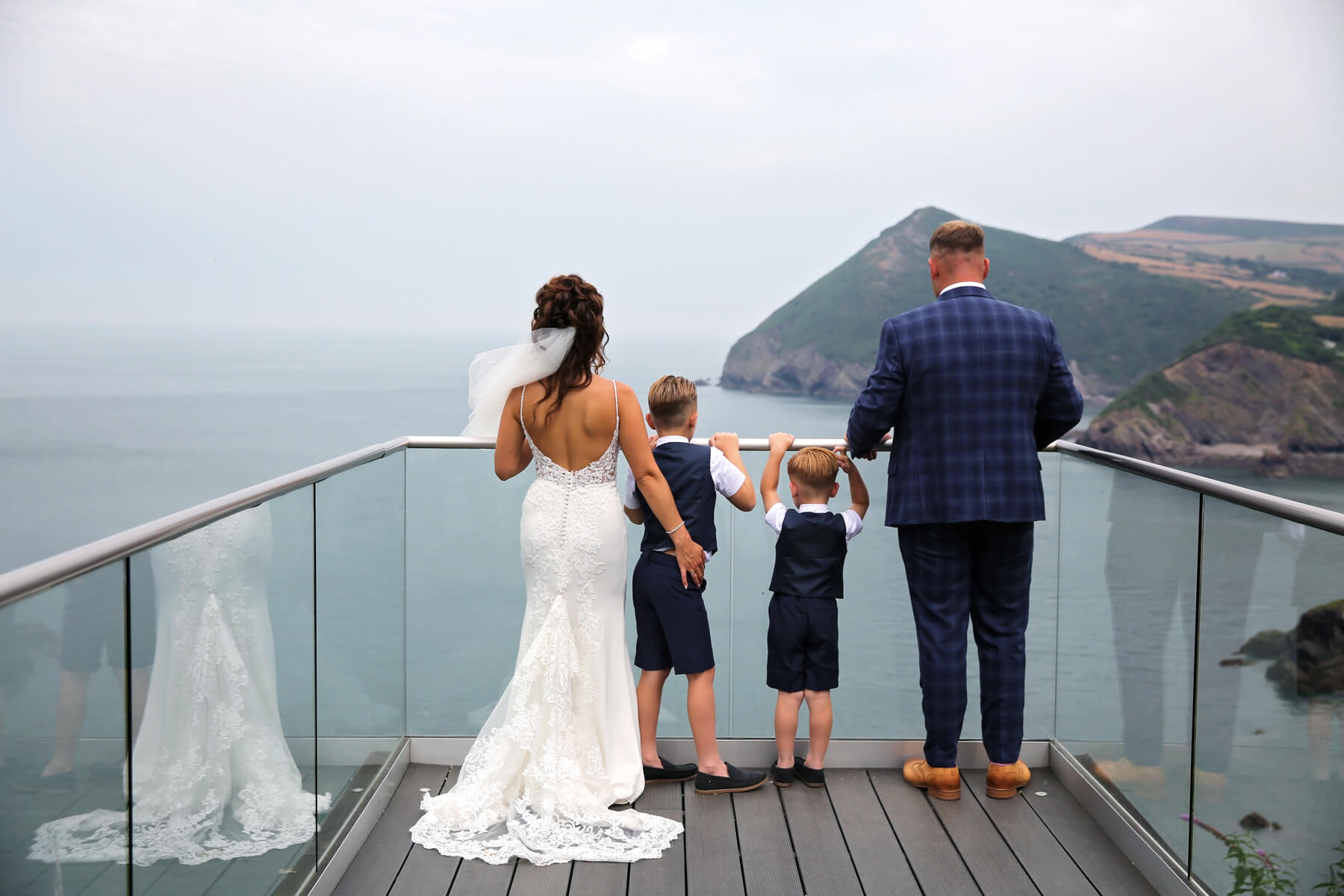 bride, groom and two little boys looking out to the sea