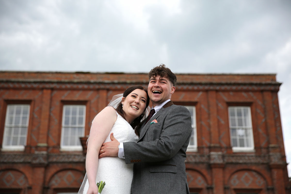 bride and groom laughing in front of a building
