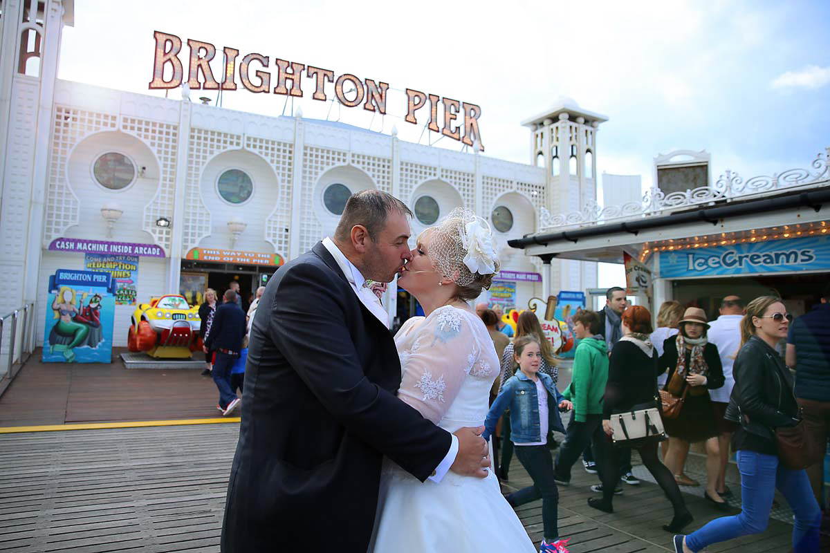 bride and groom kissing on brighton pier