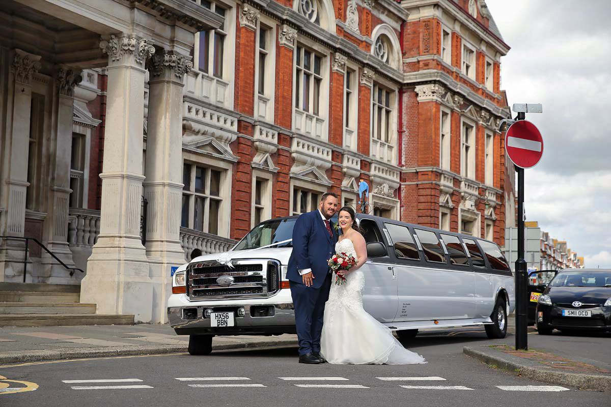 bride and groom outside Eastbourne registry office in front of there car
