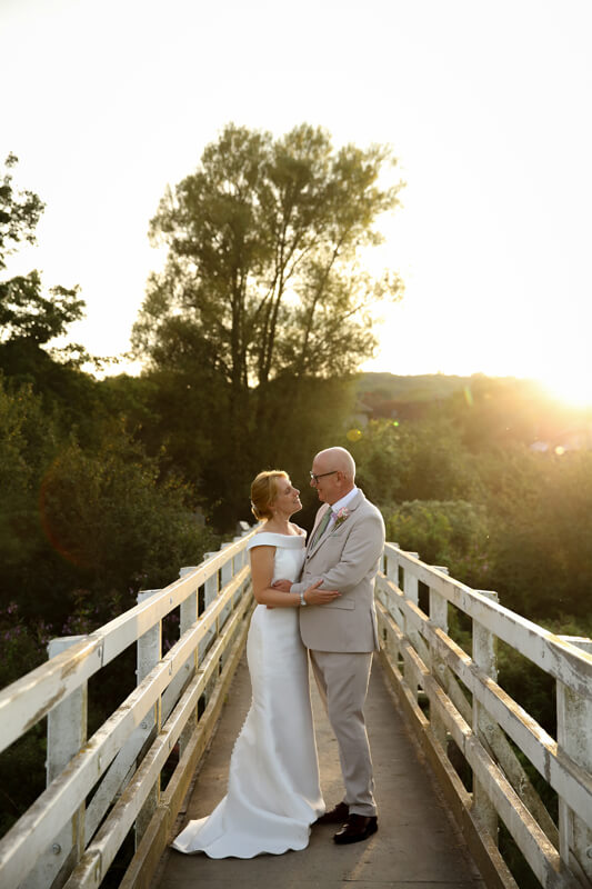 bride and groom on a bridge at sunset