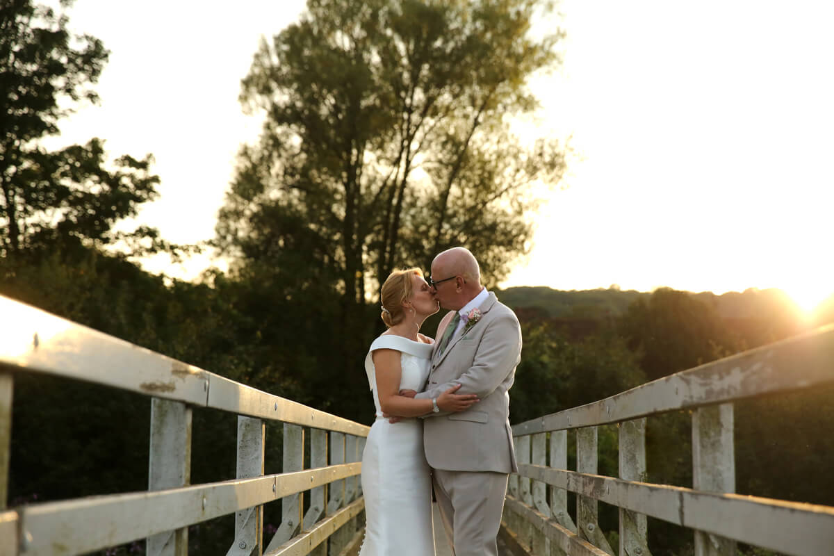 bride and groom kissing on a bridge