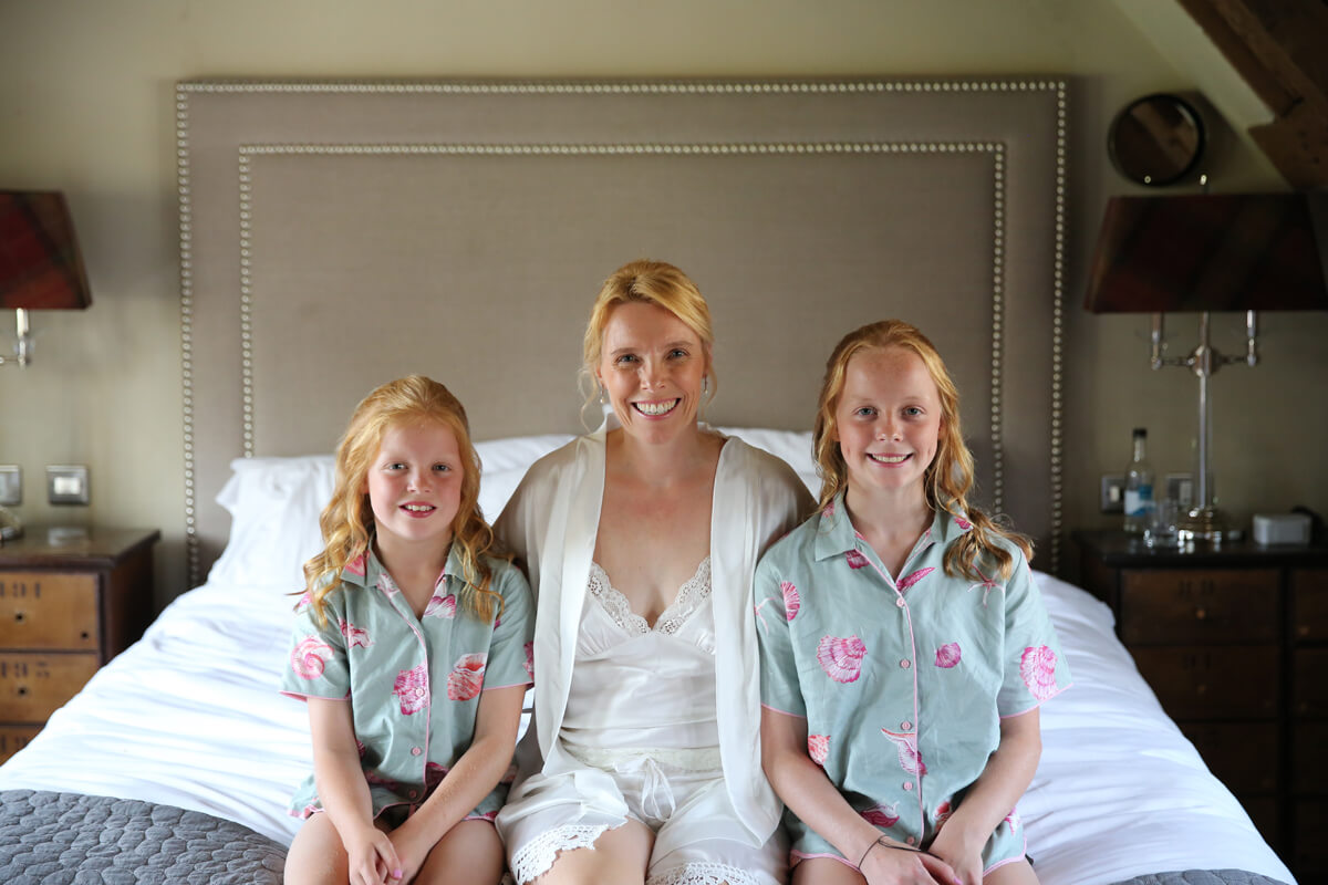 bride and flower girls sitting on a bed