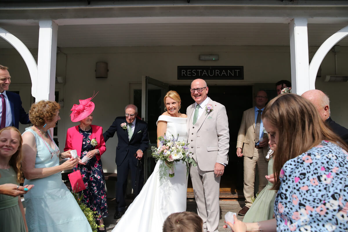 bride and groom smiling surrounded by friends and family