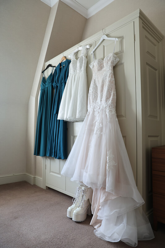 a wedding dress and bridesmaid dresses hanging